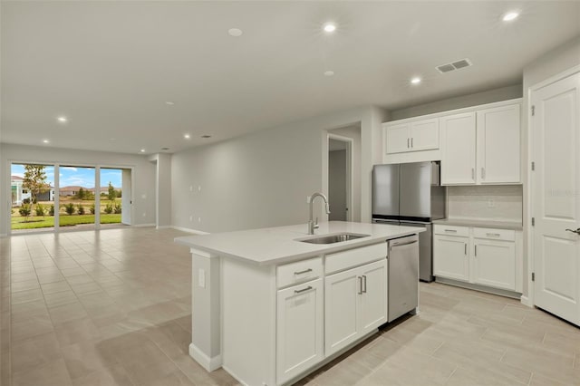 kitchen featuring sink, appliances with stainless steel finishes, an island with sink, decorative backsplash, and white cabinets