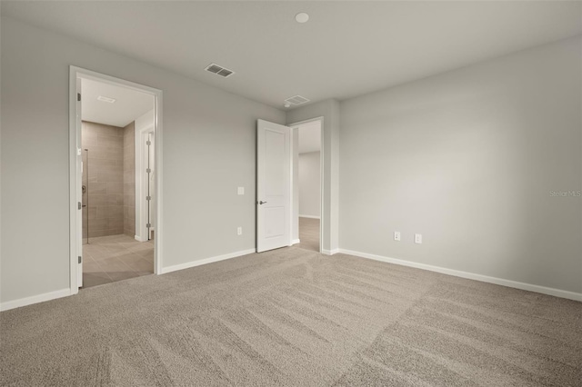 unfurnished bedroom featuring light colored carpet and ensuite bath