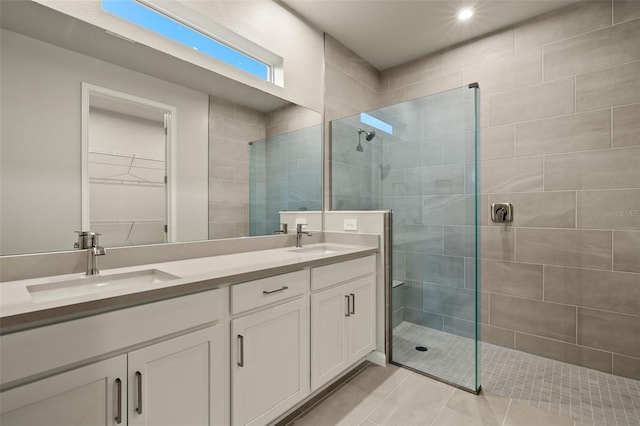 bathroom with tile patterned flooring, vanity, and tiled shower