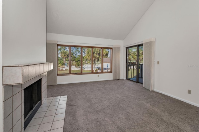 unfurnished living room featuring baseboards, high vaulted ceiling, a tiled fireplace, and light colored carpet