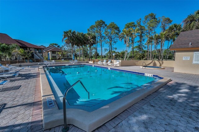 community pool with a patio area and fence