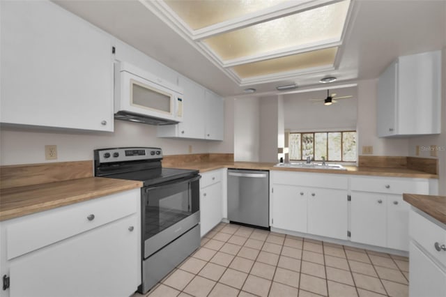 kitchen featuring light tile patterned floors, stainless steel appliances, a sink, white cabinetry, and light countertops