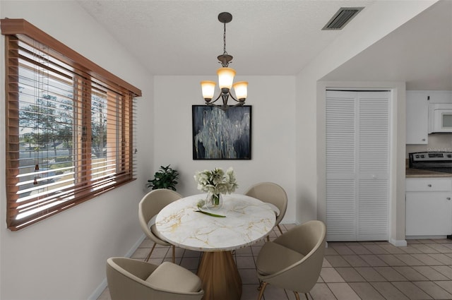 dining area with light tile patterned floors, visible vents, a chandelier, and a textured ceiling