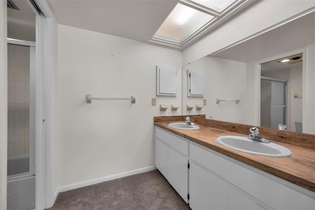 bathroom featuring double vanity, a skylight, a sink, and baseboards