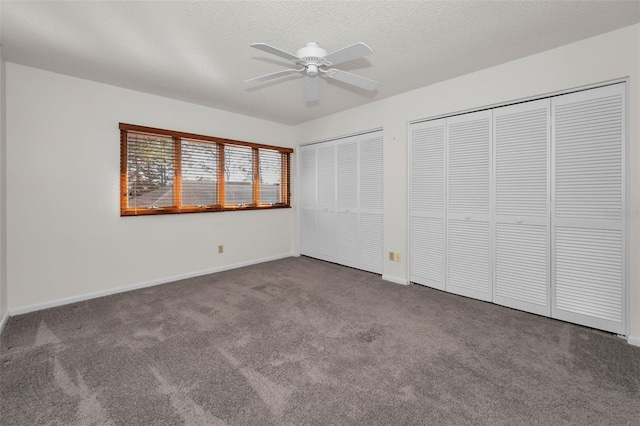 unfurnished bedroom with a textured ceiling, baseboards, multiple closets, and carpet flooring