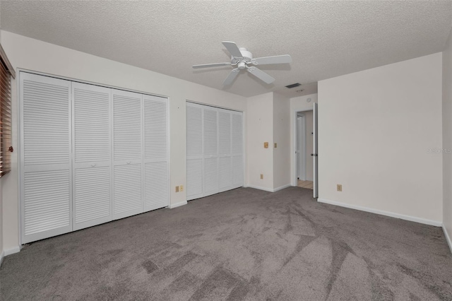 unfurnished bedroom featuring a textured ceiling, visible vents, baseboards, carpet, and two closets