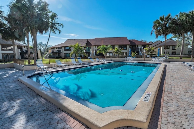 community pool featuring a residential view, fence, and a patio