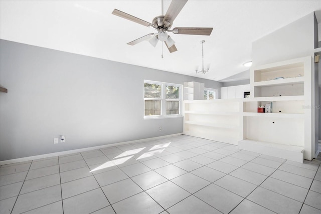 tiled empty room with built in shelves, vaulted ceiling, and ceiling fan with notable chandelier