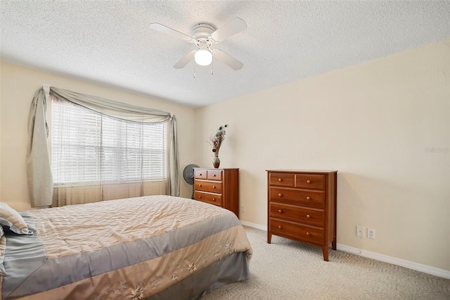 bedroom featuring ceiling fan, light colored carpet, and a textured ceiling