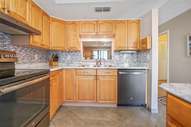 kitchen with sink, a textured ceiling, light tile patterned floors, appliances with stainless steel finishes, and backsplash