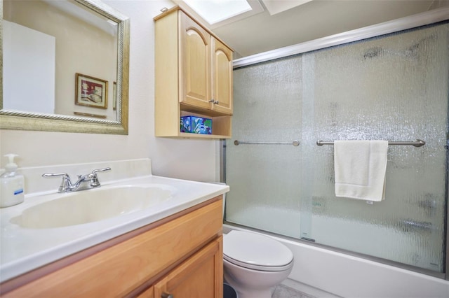 full bathroom with bath / shower combo with glass door, vanity, and toilet