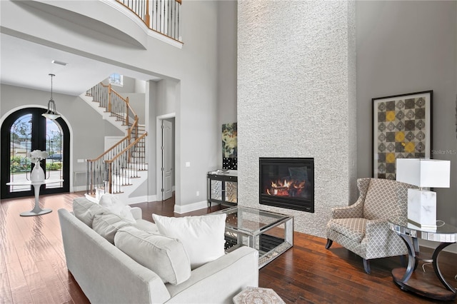 living room with a high ceiling, dark hardwood / wood-style floors, and a large fireplace