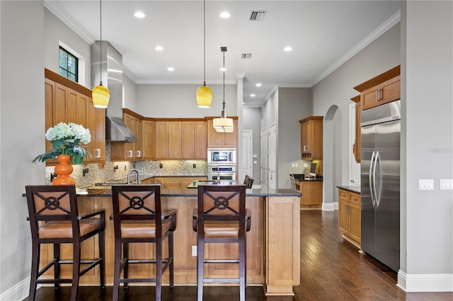 kitchen featuring hanging light fixtures, a center island with sink, built in appliances, and a kitchen breakfast bar