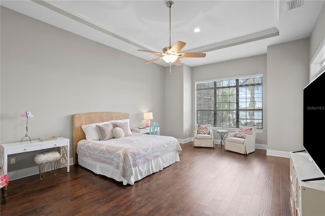 bedroom featuring dark wood-type flooring, ceiling fan, and a tray ceiling