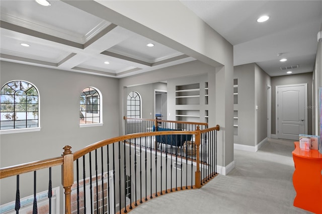 hallway featuring built in features, coffered ceiling, light colored carpet, crown molding, and beam ceiling