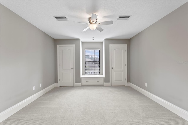 unfurnished bedroom with light carpet, ceiling fan, and a textured ceiling