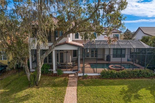 back of property featuring a swimming pool with hot tub, a patio area, glass enclosure, and a lawn