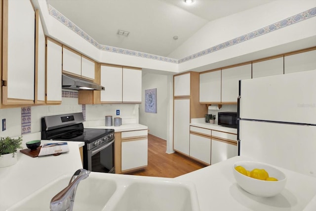 kitchen with white cabinetry, stainless steel electric range oven, vaulted ceiling, and white fridge