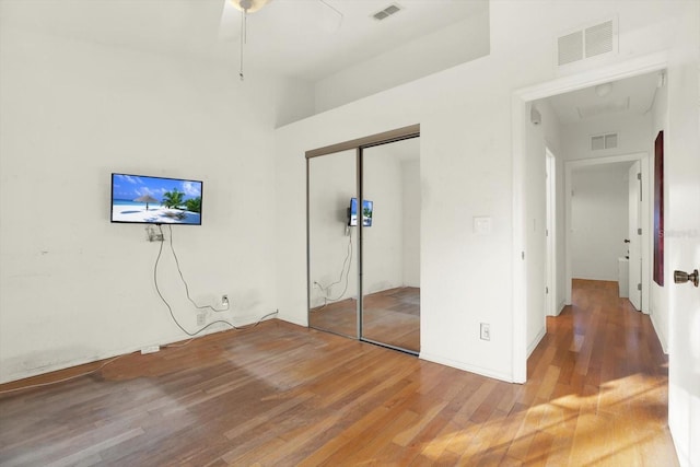 unfurnished bedroom with hardwood / wood-style flooring, ceiling fan, and a closet