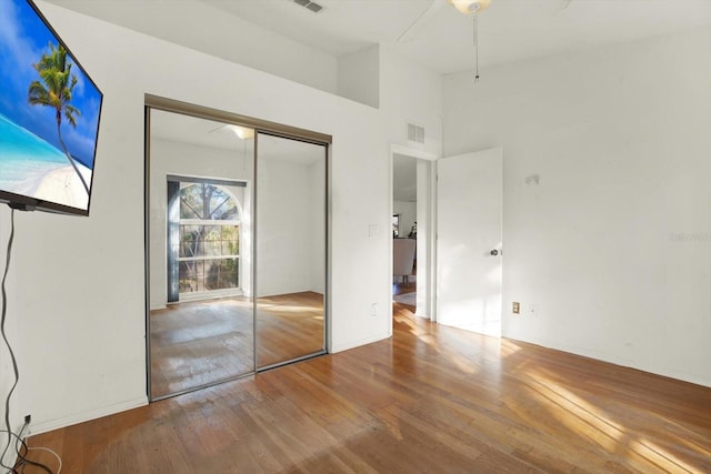 unfurnished bedroom featuring hardwood / wood-style floors, a closet, and a high ceiling