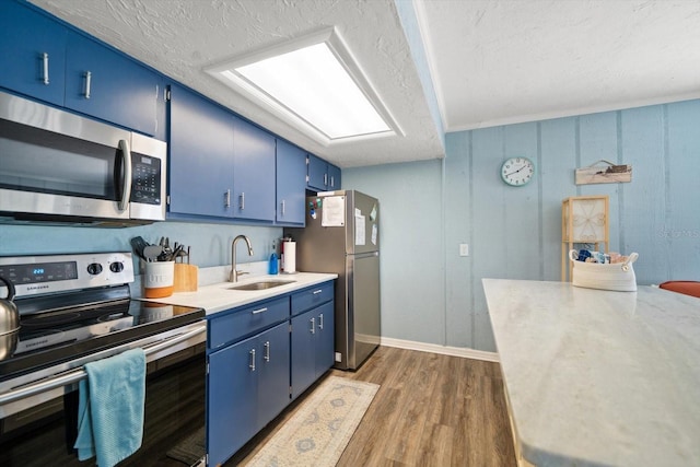 kitchen with sink, dark hardwood / wood-style flooring, stainless steel appliances, blue cabinetry, and a textured ceiling