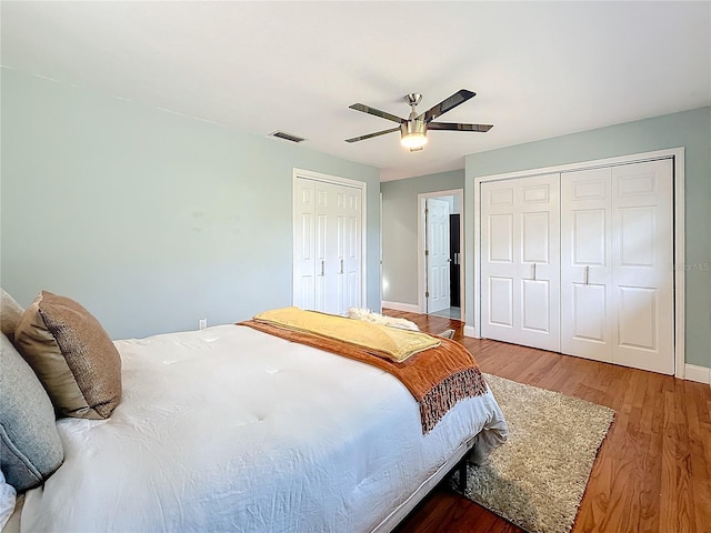 bedroom with multiple closets, ceiling fan, and wood-type flooring