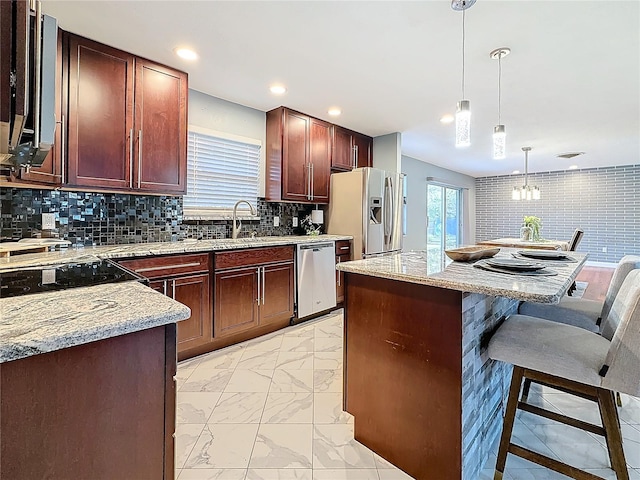 kitchen featuring appliances with stainless steel finishes, pendant lighting, tasteful backsplash, sink, and a breakfast bar area