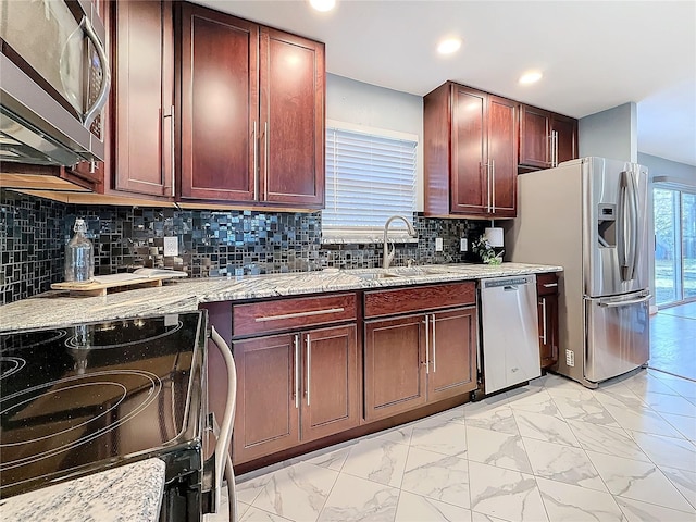 kitchen featuring stainless steel appliances, tasteful backsplash, sink, and light stone counters