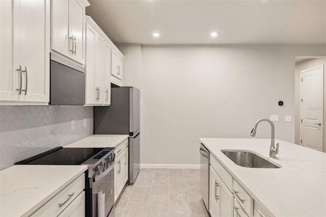 kitchen with appliances with stainless steel finishes, tasteful backsplash, white cabinetry, sink, and light stone countertops