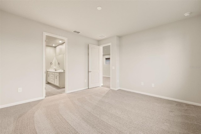 unfurnished bedroom with light colored carpet and ensuite bathroom