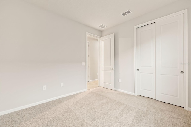 unfurnished bedroom featuring light carpet and a closet