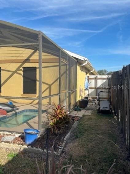 view of side of property with a fenced in pool and glass enclosure