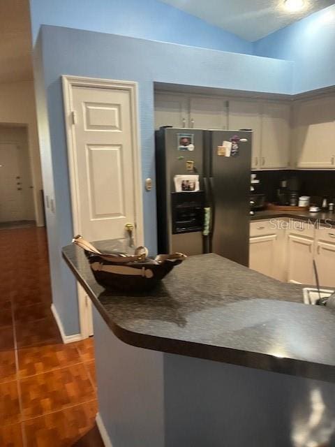 kitchen featuring white cabinetry, stainless steel fridge, and dark tile patterned floors