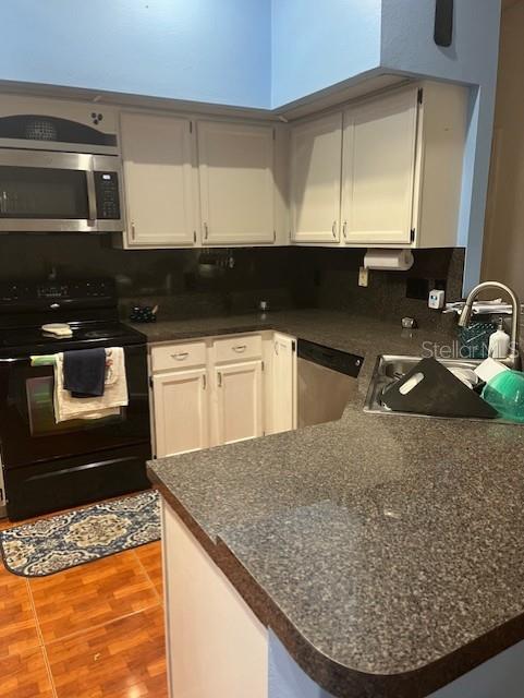 kitchen featuring white cabinetry, appliances with stainless steel finishes, kitchen peninsula, and sink