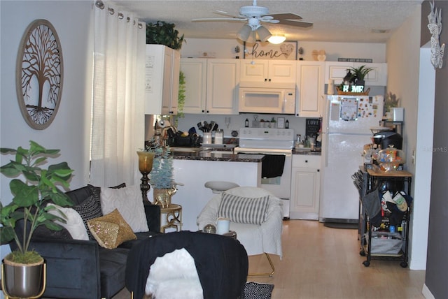 kitchen with white cabinetry, sink, white appliances, and a textured ceiling