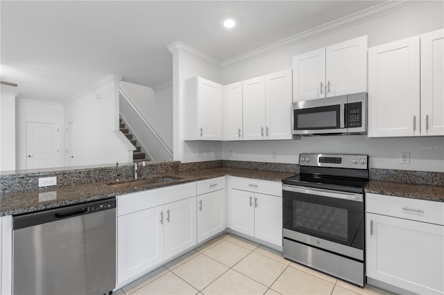 kitchen featuring stainless steel appliances, sink, dark stone counters, and white cabinets