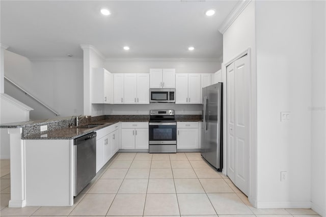 kitchen with sink, stainless steel appliances, white cabinets, kitchen peninsula, and dark stone counters