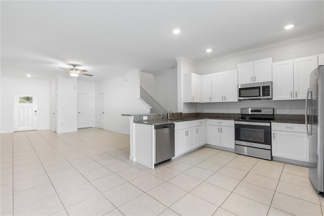 kitchen featuring dark stone countertops, light tile patterned floors, appliances with stainless steel finishes, kitchen peninsula, and white cabinets