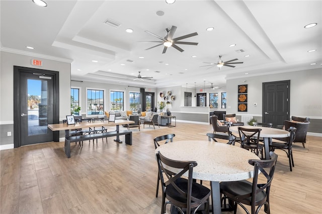 dining area with a raised ceiling, crown molding, and light hardwood / wood-style floors