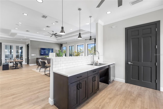 kitchen with a raised ceiling, hanging light fixtures, sink, and kitchen peninsula