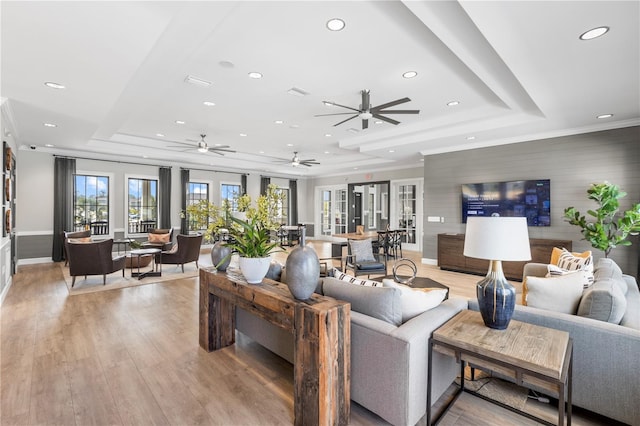 living room with a tray ceiling, ornamental molding, and light hardwood / wood-style floors