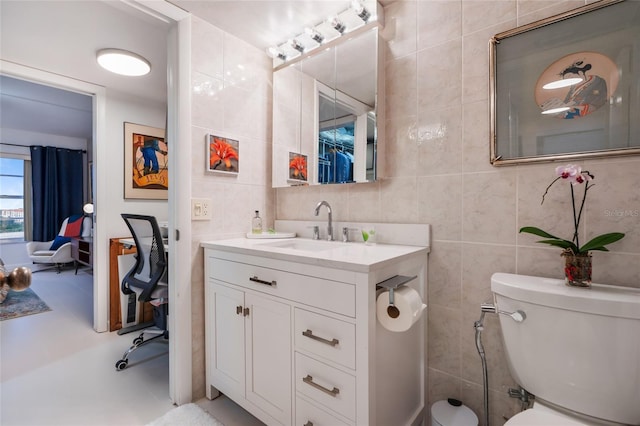 bathroom featuring vanity, tile walls, and toilet