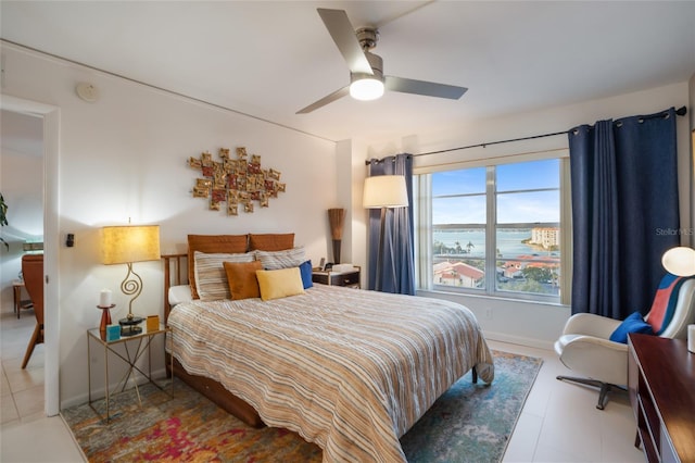 bedroom featuring ceiling fan and a water view