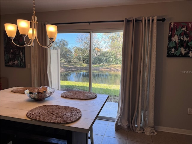 dining room with an inviting chandelier, tile patterned floors, and a water view