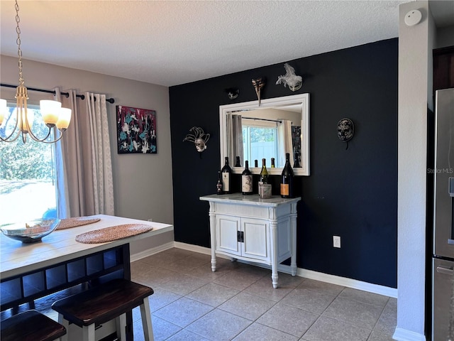 tiled dining room with an inviting chandelier, bar area, and a textured ceiling