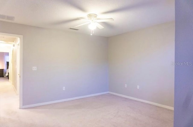 spare room with ceiling fan, light colored carpet, and a textured ceiling