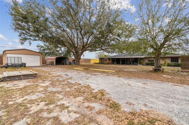 view of yard featuring a garage, an outdoor structure, and a carport