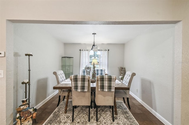 dining room with dark tile patterned flooring and a chandelier