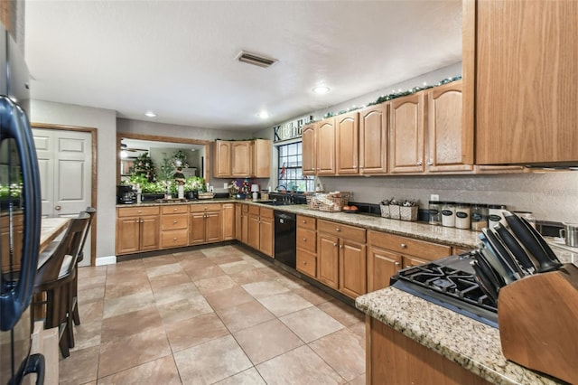 kitchen with light stone countertops, sink, light tile patterned floors, and black appliances