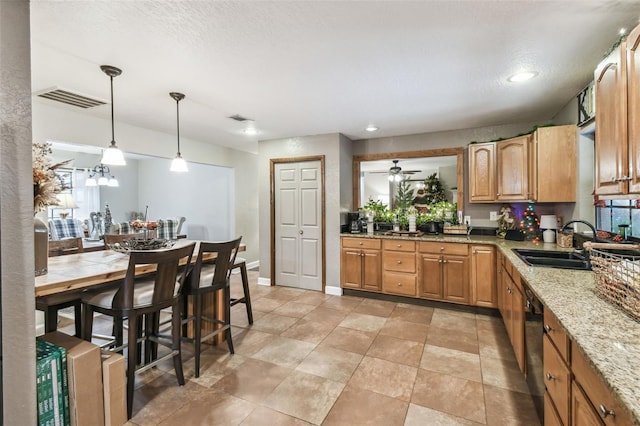 kitchen with dishwasher, sink, hanging light fixtures, light stone countertops, and a textured ceiling